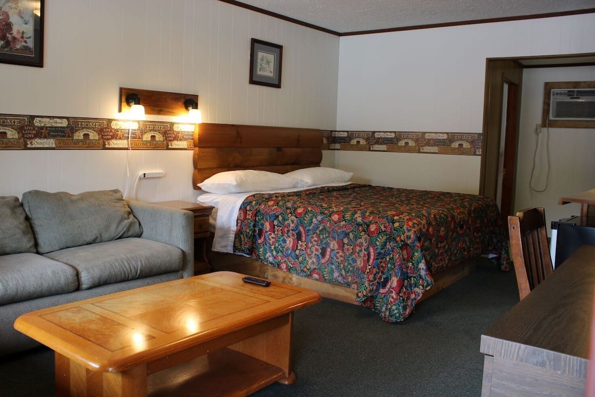 Una habitación acogedora con una cama, un sofá y una mesa de madera.