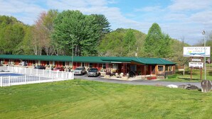 A lodge with a green roof, a covered parking area, and a sign indicating it is an American-owned family-operated business. - Two Rivers Lodge (Bryson City)