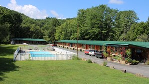 A motel with multiple rooms, a swimming pool, and a parking area. - Two Rivers Lodge (Bryson City)
