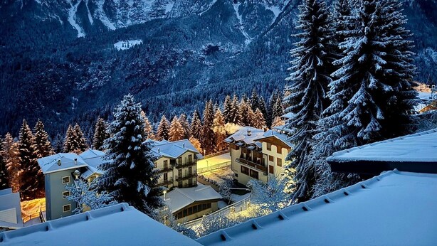 A snow-covered mountain landscape with a residential area featuring multi-story buildings and snow-laden trees. - Appartamento Marele (Folgarida)