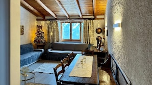 A cozy room with a wooden ceiling, a dining table with chairs, a sofa, and a Christmas tree. - Appartamento Marele (Folgarida)