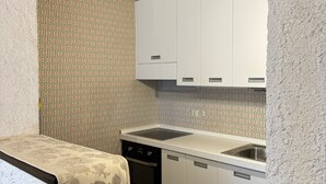 A compact kitchen with white cabinets, a built-in oven, and a sink. - Appartamento Marele (Folgarida)