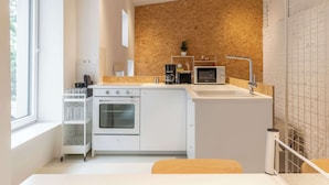 Une cuisine moderne avec des meubles blancs, un four encastré, un four à micro-ondes et une machine à café.
