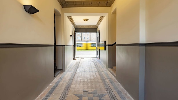 Un couloir doté d’un sol à motifs, avec un décor en forme d’étoile, et donnant sur un autobus jaune à l’extérieur.
