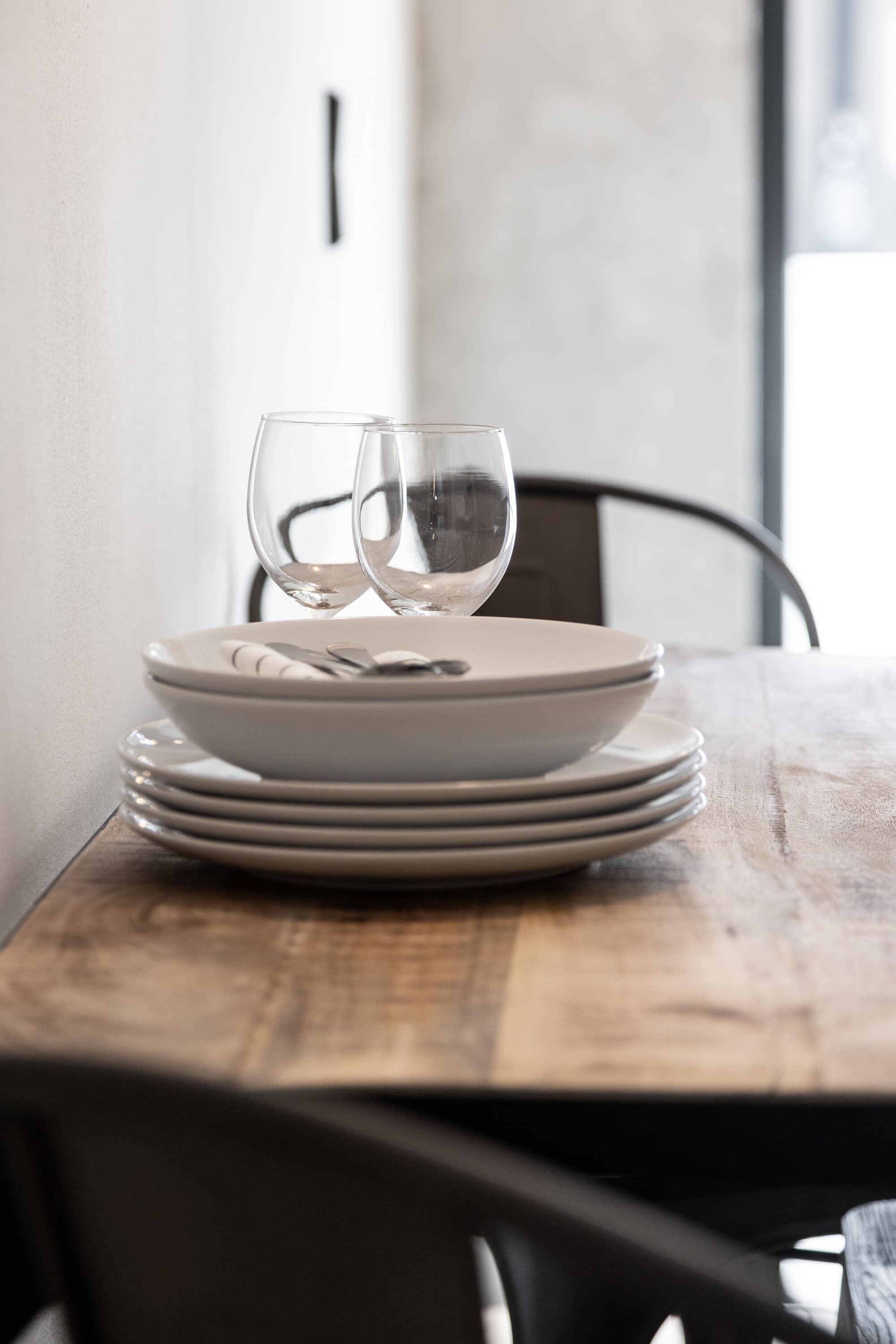 Une table à manger avec une pile d’assiettes et deux verres.