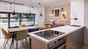 A modern kitchen with a central island, a dining area with colorful chairs, pendant lighting, and artwork on the walls. - Industrial Loft Duplex (100sqm) near Antonplatz (Berlin)