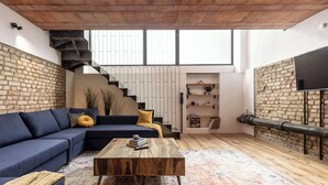 A modern living room with a blue sofa, a wooden coffee table, and a patterned rug. - Industrial Loft Duplex (100sqm) near Antonplatz (Berlin)
