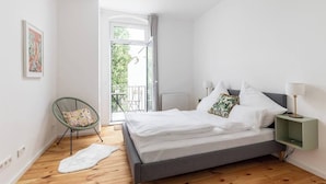 A bedroom with a bed, a chair, a small table, and a view of the outdoors. - 75sqm flat 1st occupancy, near centre & PrenzlBerg (Berlin)