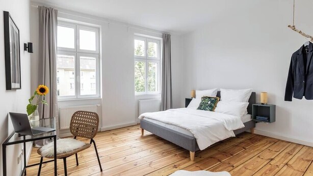 Een slaapkamer met een bed, een bureau, een stoel en een raam.
