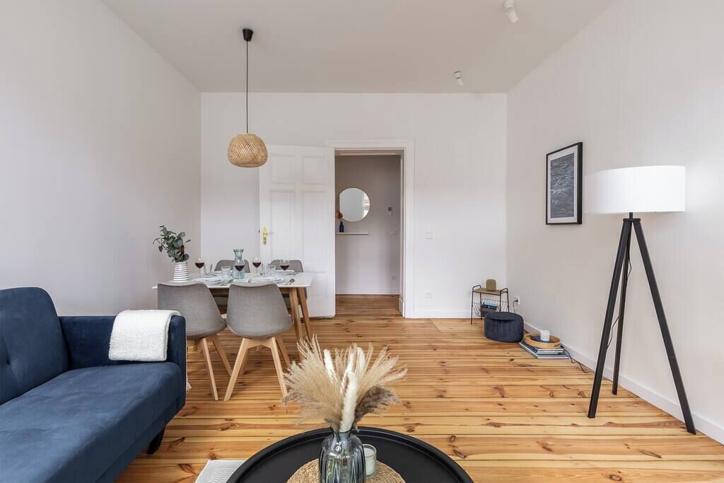 Un salon moderne avec un canapé bleu, un coin repas et une lampe.