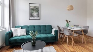 Una sala de estar moderna con un sofá color turquesa, una mesa de centro redonda y un comedor con una mesa y sillas de madera.