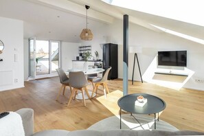 A modern living space with a dining area, a kitchen, and a TV.