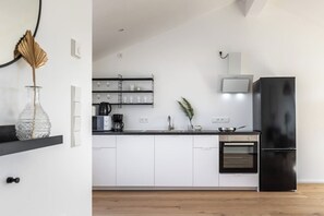 Una cocina moderna con armarios blancos, un refrigerador negro, un microondas y una estufa.