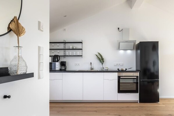 A modern kitchen with white cabinets, a black refrigerator, a microwave, and a stove.
