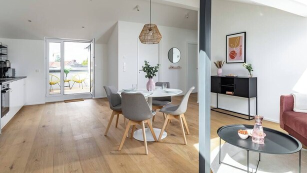 Un salon moderne comprenant un coin repas, une cuisine et un balcon.