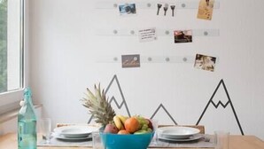 A dining area with a wooden table, blue bowl of fruit, and a pendant light. - 65 m² Apartment w. Spreeview directly at Ostkreuz (Berlin)
