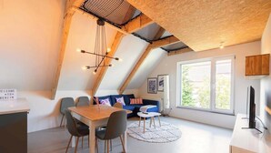 A loft-style room with a dining area, a sofa, and a TV. - Bright Hideaway (70 sqm) near BER Airport (Berlin)