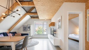 A modern loft-style apartment with a dining area, a living space, and a bedroom. - Bright Hideaway (70 sqm) near BER Airport (Berlin)