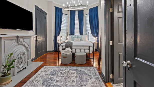 Un dormitorio con cama, mesitas de noche, televisor y candelabro.
