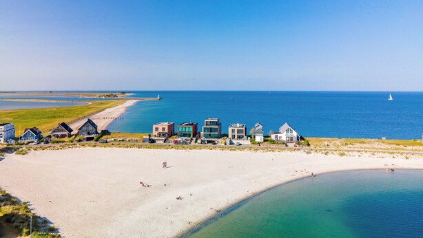 A coastal area with a sandy beach, a row of houses, and a clear view of the sea. - "Sky 65" - Exclusive penthouse with sauna & sea view at Ostsee Resort Olpenitz (Ostseeresort Olpenitz)