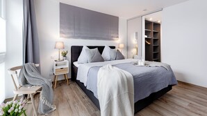 A modern bedroom with a bed, bedside tables, a chair, a mirror, and a wardrobe. - "Sky 65" - Exclusive penthouse with sauna & sea view at Ostsee Resort Olpenitz (Ostseeresort Olpenitz)