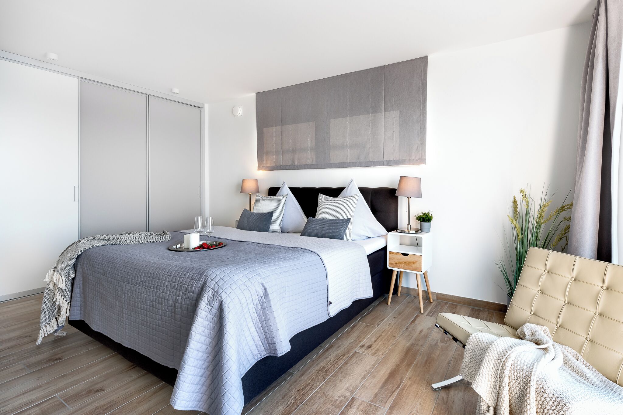 Une chambre à coucher moderne avec un grand lit, des tables de chevet, un canapé et une grande œuvre d’art accrochée au mur.