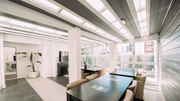 A modern office space with a long table, comfortable chairs, and a large window offering a view of the city. - Maison Work & Travel 6 - Palermo  (Buenos Aires)