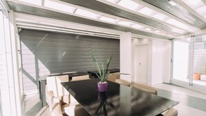 A conference room with a black table, beige chairs, and a potted plant. - Maison Work & Travel 6 - Palermo  (Buenos Aires)