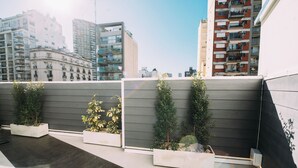 A rooftop terrace with a row of planters and a view of surrounding buildings. - Maison Work & Travel 6 - Palermo  (Buenos Aires)