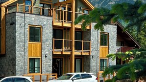 Ein modernes, mehrstöckiges Lodge-Gebäude aus Stein und Holz mit großen Fenstern und einem Balkon.