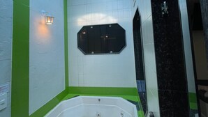 Une salle de bain moderne avec une grande baignoire, un puits de lumière et un mur d’accent vert.