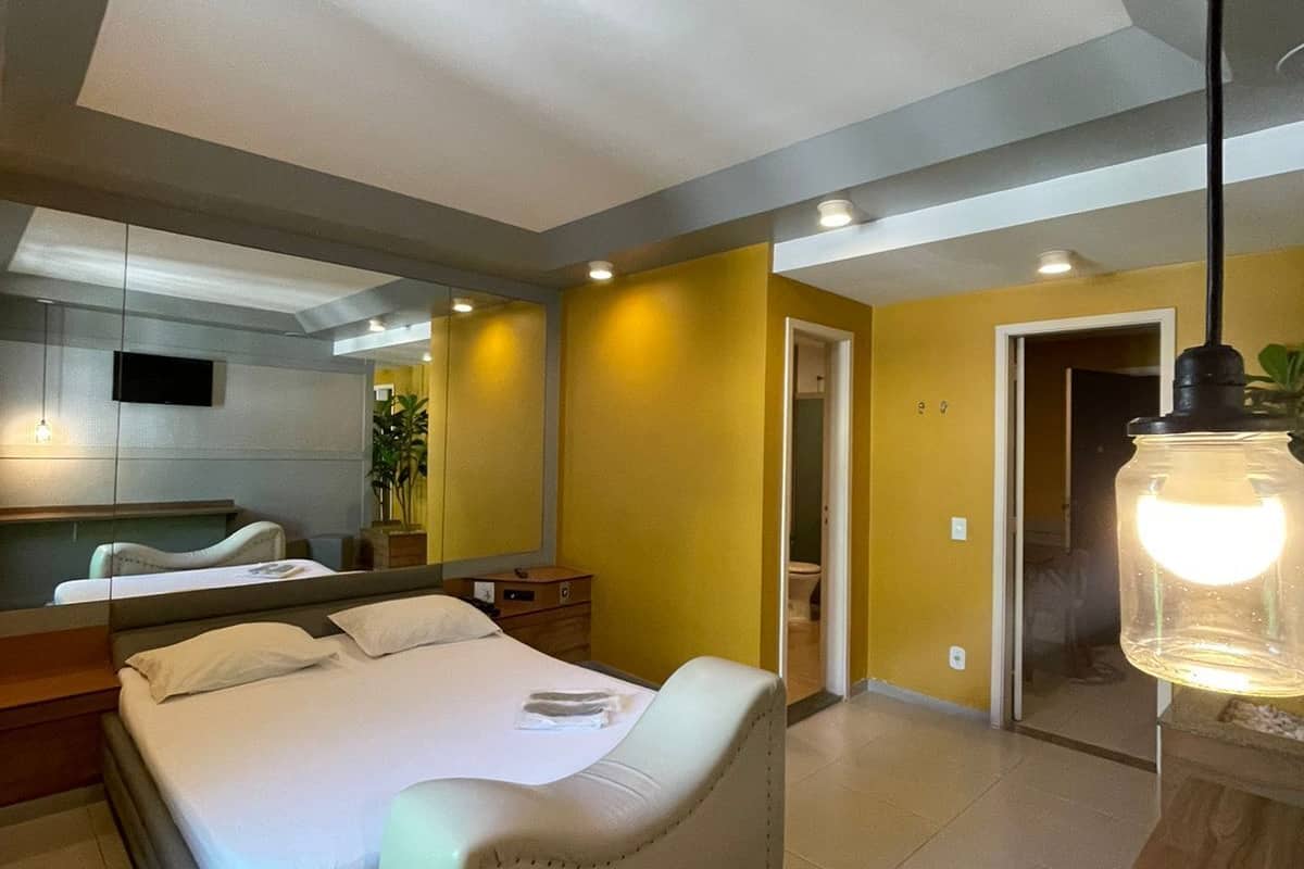 Una habitación de hotel moderna con una cama grande, un televisor de pantalla plana, una mesita de noche y un espejo.