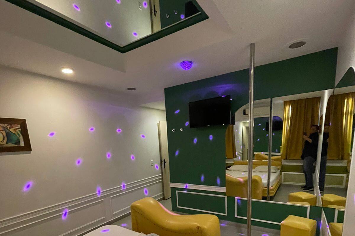 Una habitación de hotel con cama, espejo, televisión y una pequeña zona de estar.