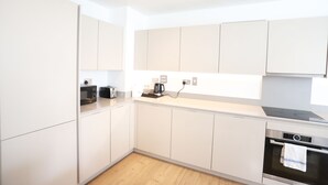 A modern kitchen with white cabinets, a built-in oven, and a microwave.