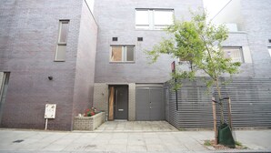 A modern building with a brick facade, a small front yard, and a metal gate.