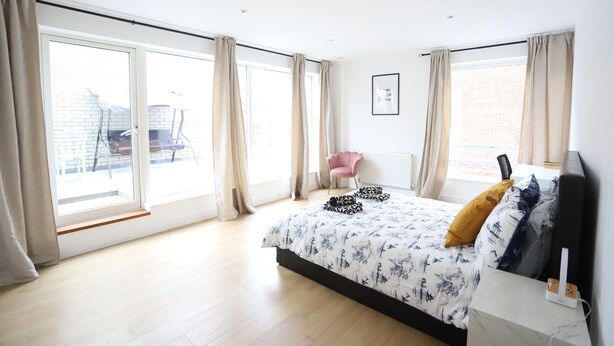 A bedroom with a large bed, a chair, and a view of the outside.
