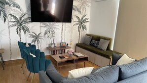 A living room with a sofa, a coffee table, and a TV mounted on the wall.