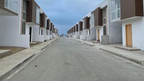 A row of modern, two-story residential buildings with large windows and a central paved street.