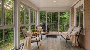 A sunroom with large windows, a wooden floor, and a seating area with chairs and a table. - Panoramic mountain view - L'Horizon doré - 12 acre (Mansonville)