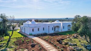 A white villa with a garden path leading to the entrance, surrounded by olive trees and a view of the countryside. - Villa Pajaro Ostuni Piscina a Sfioro e Vista Panoramica (Puglia)