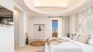 A bedroom with a large bed, a ceiling light, a door leading to a balcony, and a wall-mounted decorative panel. - Villa Pajaro Ostuni Piscina a Sfioro e Vista Panoramica (Puglia)