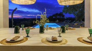 A dining table set for two with a view of a pool and sunset. - Villa Pajaro Ostuni Piscina a Sfioro e Vista Panoramica (Puglia)