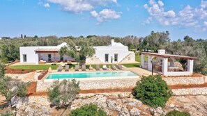 Eine moderne Villa mit Swimmingpool, Sitzgelegenheit im Freien und einer Mauer aus Naturstein.