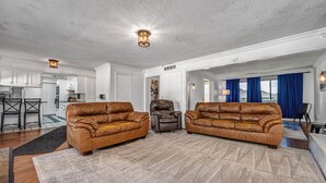 A spacious living room with two leather sofas, a coffee table, and a rug.