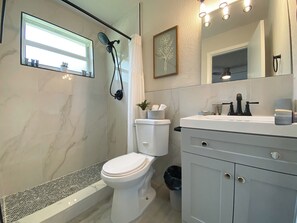 Un baño moderno con ducha, inodoro y tocador.