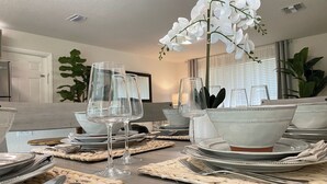 A dining table set with clear glassware, white bowls, and woven placemats.