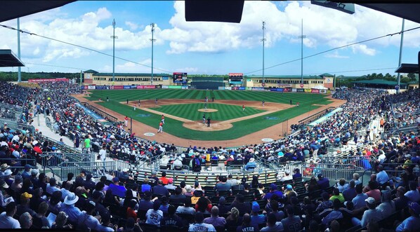 Un estadio de béisbol con varios niveles de asientos, un amplio campo de juego y un marcador.