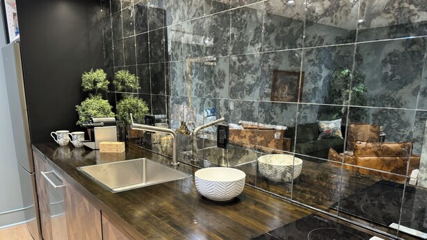 A modern kitchen with a black countertop, stainless steel sink, and a black induction cooktop.