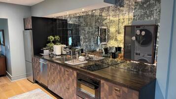 Una cocina moderna con salpicadero de mármol, electrodomésticos integrados y una isla central con fregadero y escurreplatos.