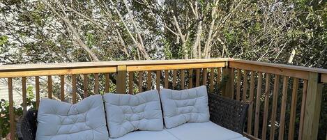 A white sectional sofa with black metal legs on a wooden deck.